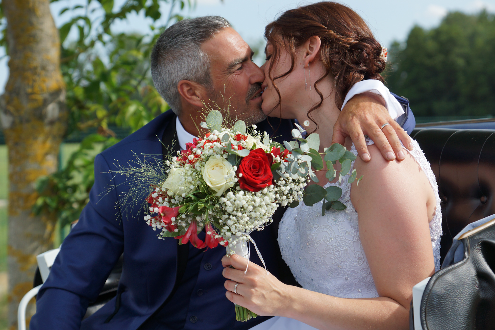Baiser de mariés avec bouquet au premier plan