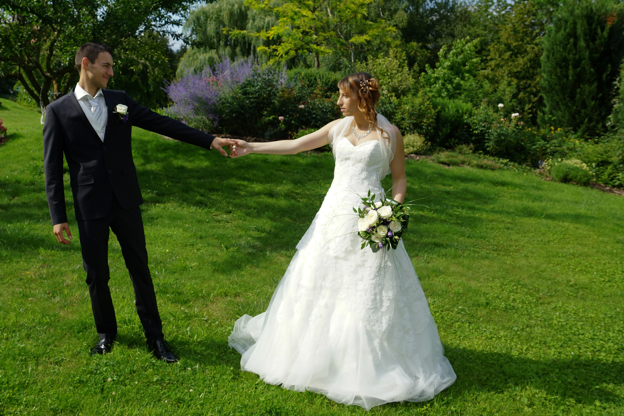 Couple de mariés se tenant par la main dans un jardin